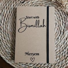 a book sitting on top of a wicker table next to a straw mat with the words start with bismillah