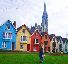 a woman is standing in front of some colorful houses with a steeple on top