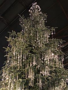 a very tall christmas tree with lots of lights hanging from it's sides in a building