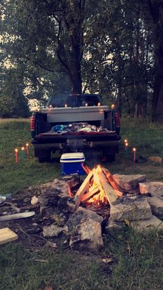 a truck parked next to a campfire with candles on the ground in front of it