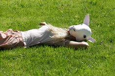 a doll laying on its back in the grass with a rabbit mask on it's head