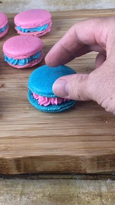 a person is making pink and blue macaroons