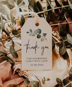 a thank you tag hanging from a wire with greenery around it and the words'thank you'written on it