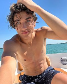 a shirtless young man sitting on top of a boat