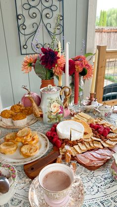 a table filled with food and drinks on top of a white table cloth next to a window