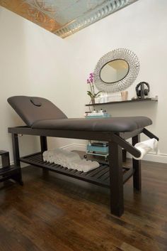 a massage table in the corner of a room with a mirror on the wall above it