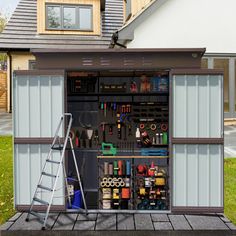 an outdoor storage shed with tools in the door and shelves on the outside, next to a ladder