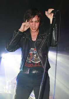 a young man holding a microphone up to his ear while standing in front of a stage