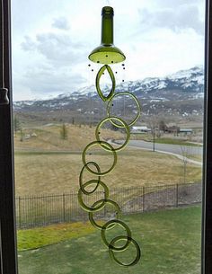 a wind chime hanging from the side of a window in a house with mountains in the background