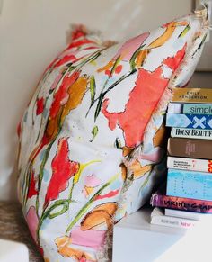 a pile of books sitting on top of a table next to a pillow