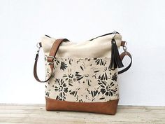 a handbag sitting on top of a wooden table next to a white wall with black and brown flowers