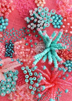 there are many beaded flowers on the pink table cloth, and one is blue