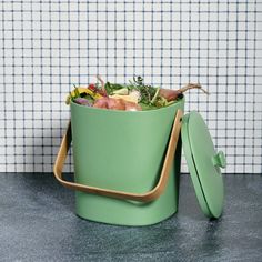 a green trash can sitting on top of a counter