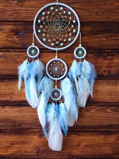 a blue and white dream catcher on a wooden surface with beads, feathers and beads