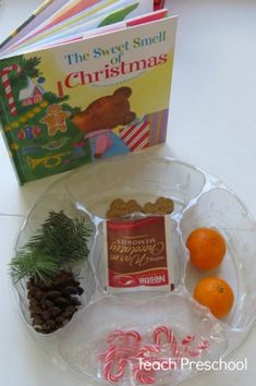 a plate with candy canes, cookies and an orange on it next to a book about the sweet smell of christmas