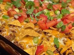 a tray filled with nachos topped with cheese and tomatoes