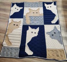 a crocheted blanket with cats on it sitting on top of a wooden floor