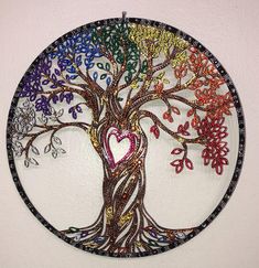 a colorful tree with hearts in the center on a white wall hanging from a hook