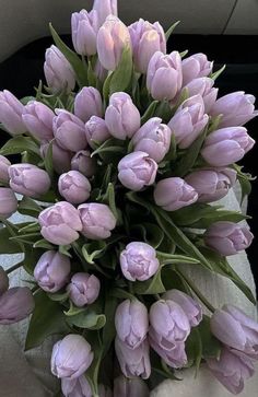 a bouquet of pink tulips sitting on top of a white cloth covered table