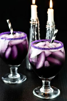 two glasses filled with purple liquid on top of a table