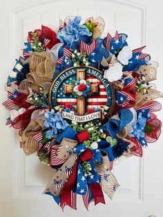 a patriotic wreath with an american flag and a cross on it, hanging from the front door