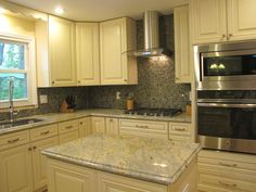 a kitchen with white cabinets and granite counter tops, stainless steel appliances and an oven