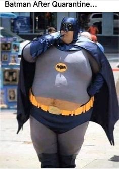 a man dressed as batman is walking down the street with his hands on his hips