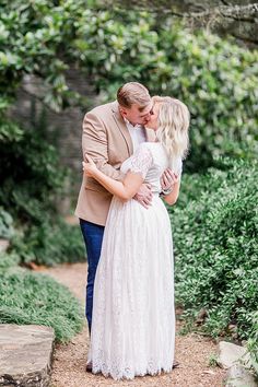 a man and woman embracing each other in front of trees