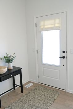 a white door with a black table and potted plant next to it on the floor