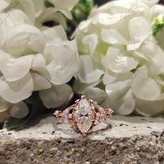 a close up of a ring on a rock with flowers in the background and white hydrangeas behind it