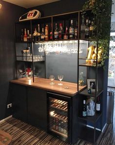 a bar with wine glasses and bottles on the shelves in a room that has wood flooring