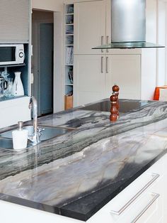 a kitchen with marble counter tops and white cabinets in the back drop off cabinetry