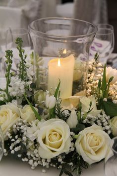 white flowers and greenery are arranged on a table