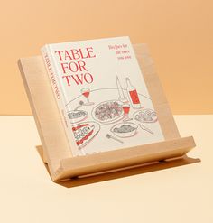 a table for two book sitting on top of a wooden stand