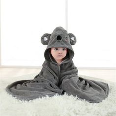 a little boy in a koala costume laying on a fluffy white rug with his eyes closed