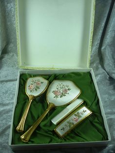 three golden spoons in a white box on a green cloth covered tablecloth with pink flowers