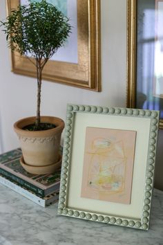 a small potted plant sitting on top of a table next to a framed painting