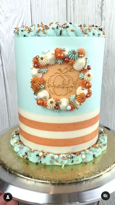 a blue and orange striped cake with shells on the top is sitting on a silver platter