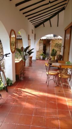 an outdoor patio with tables and chairs, potted plants and mirrors on the wall