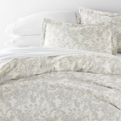 the comforter is made up with white and gray flowers on it's bed