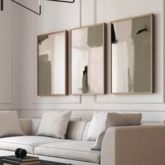 three paintings hang on the wall above a white couch and coffee table in a living room