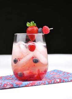 a glass filled with ice and strawberries on top of a table