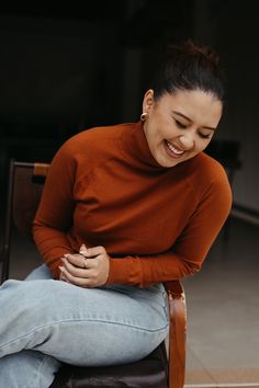 a woman sitting in a chair smiling at the camera