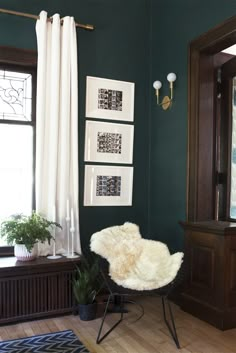 a living room with green walls and pictures on the wall, including a white chair