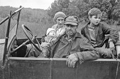 an old black and white photo of three people in a truck with the driver looking at the camera