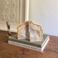 two books are stacked on top of each other in front of a white framed wall