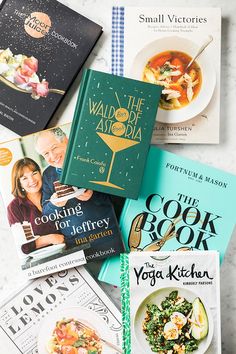 several cookbooks are stacked on top of each other in front of a marble table