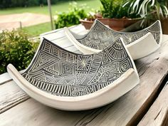 two black and white plates sitting on top of a wooden table next to potted plants