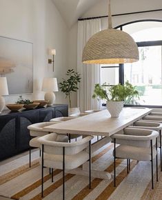 the dining room table is surrounded by white chairs and an oval chandelier above it