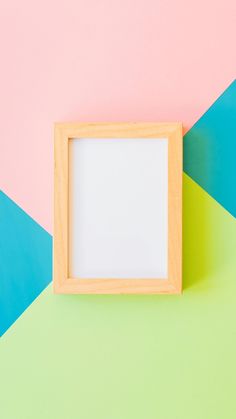 an empty wooden frame sitting on top of a colorful wall next to a green and pink background